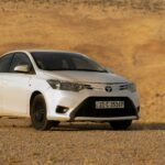 A modern white Toyota car parked in a vast desert setting, perfect for automotive imagery.